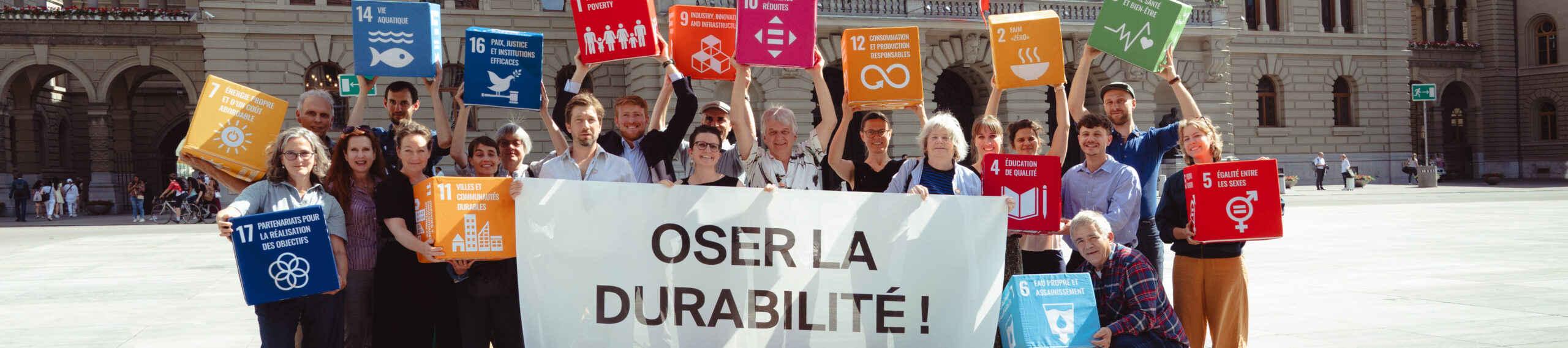 Un groupe de gens sur la Place fédérale avec une bannière qui dit "Oser la durabilité"